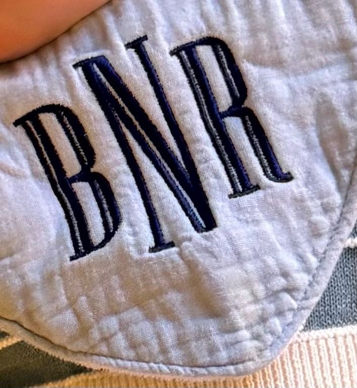 Baby item embroidered with a three-letter monogram in navy